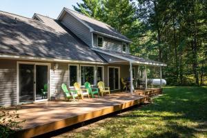 een huis met een terras met stoelen erop bij Bissell Creek Woodside Cottage in Williamsburg