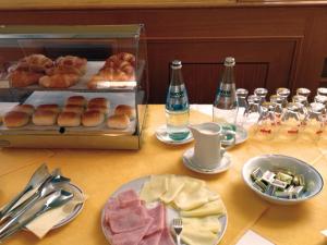 einen Tisch mit einem Tablett mit Donuts und einer Schachtel Brot in der Unterkunft Albergo Roma in Tolmezzo