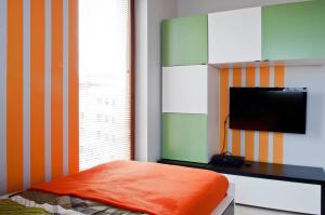 1 dormitorio con TV y 1 cama con almohada naranja en Sunny Stay Apartment, en Świnoujście