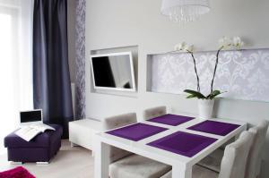 ein Esszimmer mit einem weißen Tisch und einem lila Teppich in der Unterkunft Sunny Stay Apartment in Świnoujście