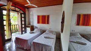 a room with two beds and a table in it at Pousada Ilha De Boipeba in Ilha de Boipeba