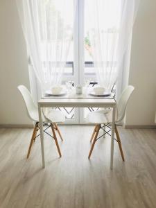 凱奇凱梅特的住宿－Belvárosi Stúdió Apartman，餐桌、白色椅子和窗户