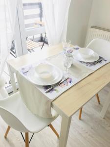 a white dining room table with white plates on it at Belvárosi Stúdió Apartman in Kecskemét