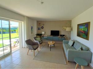 uma sala de estar com um sofá e cadeiras e uma televisão em Apartment Vista Verde em Cabanas de Tavira