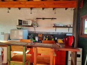 a kitchen with a counter with chairs and a table at Complejo La Pausa in Punta Del Diablo