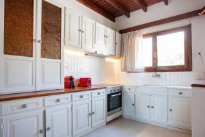 a white kitchen with white cabinets and a window at Chania Living Stories Villa with Piano in Chania