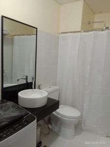 a bathroom with a sink and a toilet and a mirror at The Rochester Condo in Manila