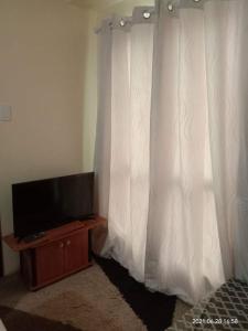 1 dormitorio con TV y cortina blanca en The Rochester Condo, en Manila