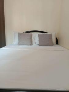 a white bed with two pillows on top of it at The Rochester Condo in Manila
