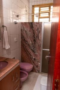 uma casa de banho com um WC cor-de-rosa e um lavatório. em Cacau Hostel em Goiânia
