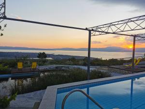a pool with a view of the ocean at sunset at Villa Suzi Donkey farm with seaview in Šmrika