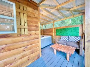 un porche de una cabaña de madera con un banco en New Tiny cabin Hot tub Firepit Fenced yard, en Sevierville