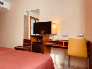 um quarto de hotel com uma cama e uma secretária com uma televisão em Torrijos em Cheste