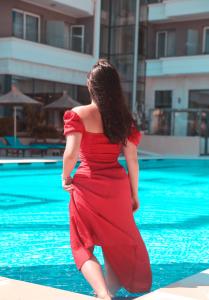 a woman in a red dress standing in the water at Kraal Hotel Vlore in Vlorë