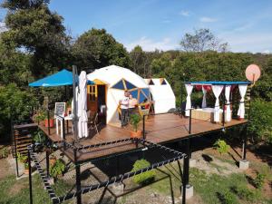 a man standing on a deck in front of a yurt at Glamping Girardot & Hotel Puerta Del Sol Girardot in La Virginia