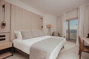 a bedroom with a large white bed and a desk at Atlantica Bay - Adults Only in Limassol