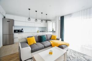 a living room with a gray couch and yellow pillows at Elegant & Spacious – Central Apartment in Oradea