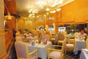 a restaurant with tables and chairs and people in it at Grand Palace Hotel in Miri