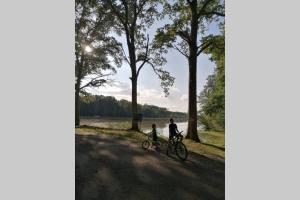 un hombre y un niño montando una bicicleta junto a un lago en LE COTTAGE DES SABLONS près du zoo de Beauval, en Saint-Romain-sur-Cher