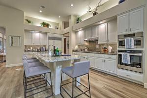 a kitchen with white cabinets and a large island with bar stools at Pet-Friendly Glendale Oasis with Pool and Hot Tub! in Phoenix