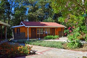 una pequeña casa en medio de un jardín en Hotel de Montaña Suria en San Gerardo de Dota