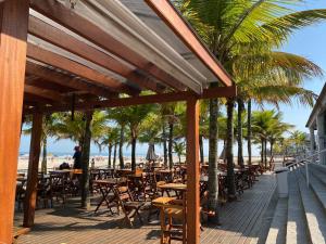 una terrazza in legno con tavoli, sedie e palme di Apartamento na Praia Grande - Aviação a Praia Grande