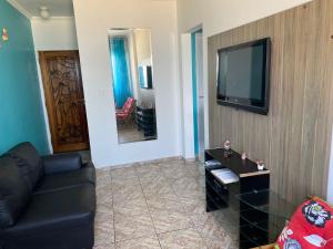 un soggiorno con divano e TV a schermo piatto di Apartamento na Praia Grande - Aviação a Praia Grande