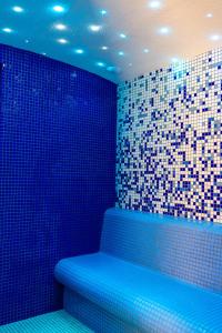 a bathroom with a blue tub with a tiled wall at Hotel & SPA Hetman in Siedlce