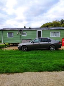 a car parked in front of a green house at Billing Aquadrome in Great Billing
