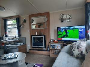 a living room with a tv and a couch at Haggerston Castle 3 Bedroom Deluxe Holiday Home in Cheswick