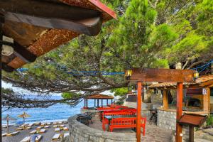 a group of tables and chairs at a restaurant by the water at Hotel Plaza Lucice in Petrovac na Moru