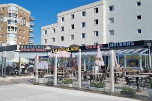 un restaurante con mesas y sillas frente a un edificio en La plage Superbe studio refait à neuf en Calais