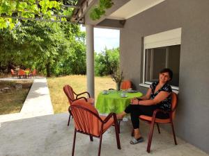 una mujer sentada en una mesa en un patio en Celtis Shade House en Virpazar