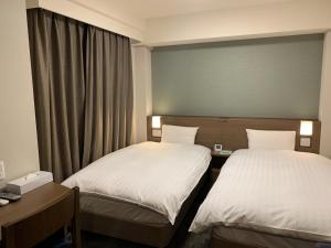 Dormy Inn EXPRESS Sendai Seaside في سيندايْ: غرفة فندقية بسريرين ونافذة