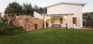 Casa blanca con pared de piedra y patio en Green House, en Siniscola