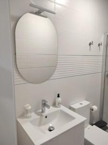 uma casa de banho branca com um lavatório e um espelho em APARTAMENTO TURISTICO LYRA BAENA em Baena