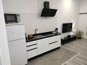 uma cozinha com armários brancos, um lavatório e uma televisão em APARTAMENTO TURISTICO LYRA BAENA em Baena