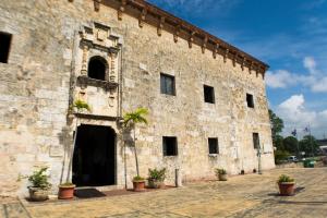 an old stone building with a palm tree in front at Malecon Rooms y Hotel in Santo Domingo