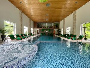 une grande piscine avec des chaises vertes dans un bâtiment dans l'établissement Complex Turistic Magura, à Măgura