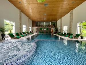 a large swimming pool with green chairs in a building at Complex Turistic Magura in Măgura