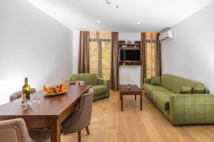 ein Wohnzimmer mit einem grünen Sofa und einem Tisch in der Unterkunft Hotel Plaza Lucice in Petrovac na Moru