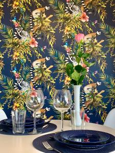 a table with wine glasses and a floral wallpaper at Madagascar Apartman Keszthely in Keszthely