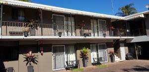 un edificio de apartamentos con sillas y plantas en el balcón en Gold Coast Airport Motel - Only 300 Meters To Airport Terminal en Gold Coast