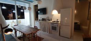 a kitchen with a wooden table and a white refrigerator at Casa Mediterranea Jacuzzi riscaldata con Caminetto in Specchiolla