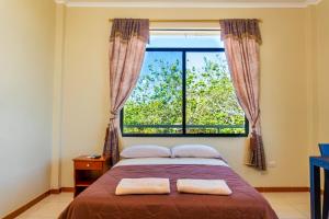 una camera con un letto e una grande finestra di Cucuve Eco Hostal a Puerto Baquerizo Moreno