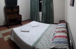 a bedroom with a bed and a dresser and a television at APARTAMENTO, CENTRO DE LA CUIDAD in Cochabamba