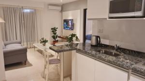 a kitchen with a sink and a living room at Nidale Suites 2 in La Rioja