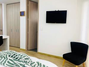 1 dormitorio con 1 cama, 1 silla y TV en Loft CHICÓ 103, parqueadero, Wifi 200 mgbs, Smart tv, en Bogotá