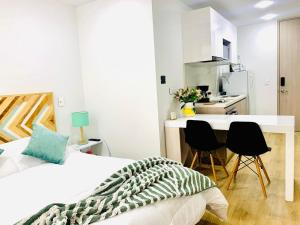 a white bedroom with a bed and a kitchen at Loft CHICÓ 103, parqueadero, Wifi 200 mgbs, Smart tv in Bogotá +8 photos