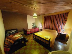 Munay EcoHostal - Cabañas de Adobe في تينوغاستا: غرفة نوم بسريرين وكرسي فيها
